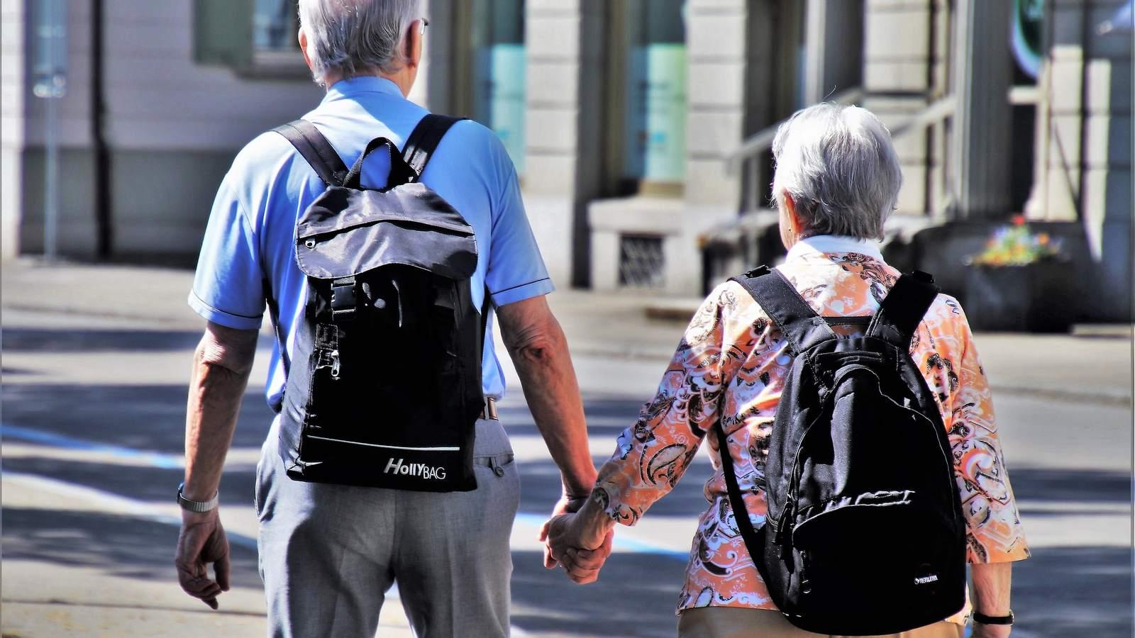 Couple de retraités vu de dos, se tenant la main