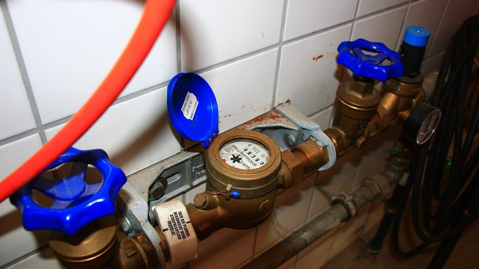 Compteur d'eau domestique et ses robinets d'arrêt bleus montés sur une canalisation