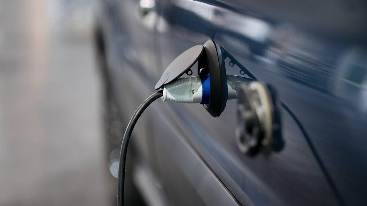 Câble de recharge branché sur la prise d'une voiture électrique bleue